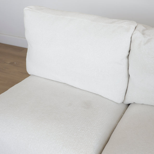 Gros plan sur le tissu bouclette blanc et les coussins moelleux d’un canapé moderne.