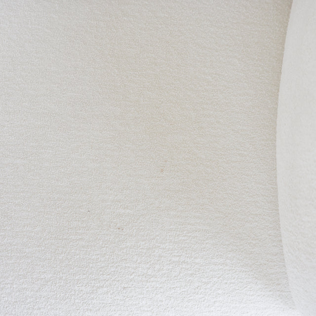 Gros plan sur le tissu bouclette blanc d’un canape, montrant sa texture douce et uniforme.