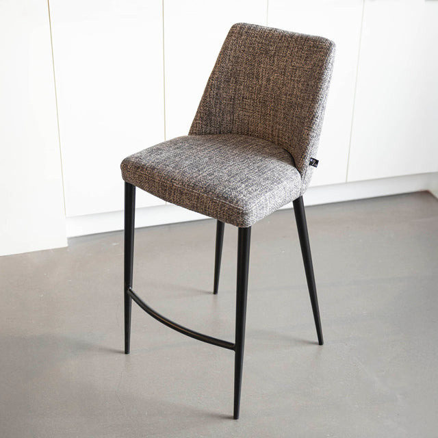 Tabouret de bar design avec assise en tissu brun/gris et pieds en metal noir, ideal pour cuisine moderne.