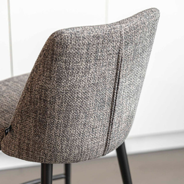 Tabouret de bar design avec assise en tissu brun/gris et pieds en metal noir, ideal pour cuisine moderne.