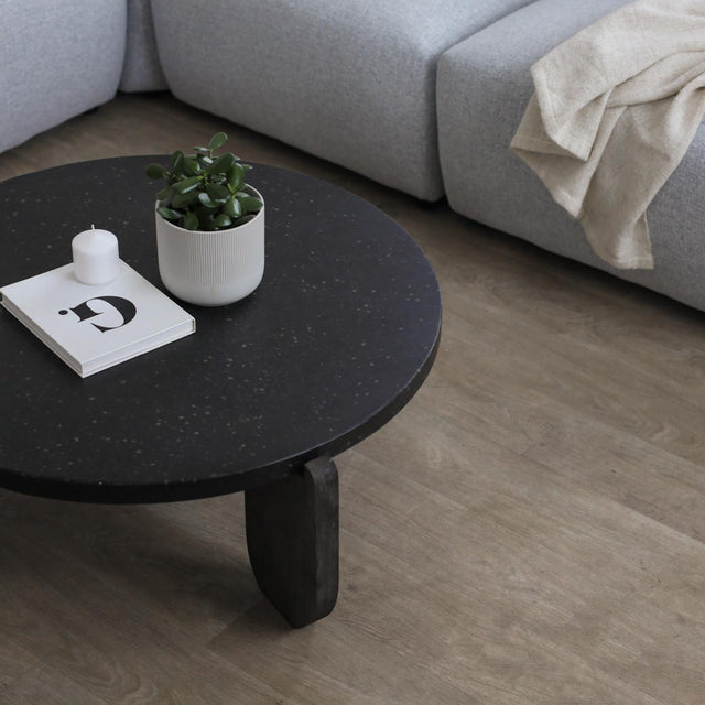 Table basse ronde noire avec pied en bois fonce et decor minimaliste.