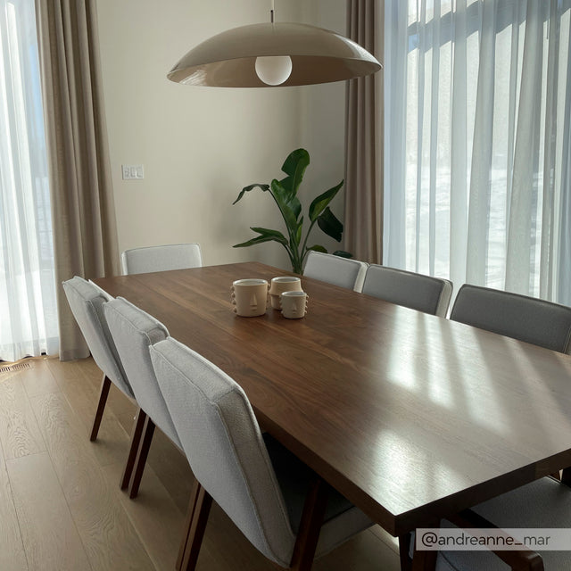 Table en bois avec chaises grises modernes et tasses en ceramique, baignee de lumiere naturelle.