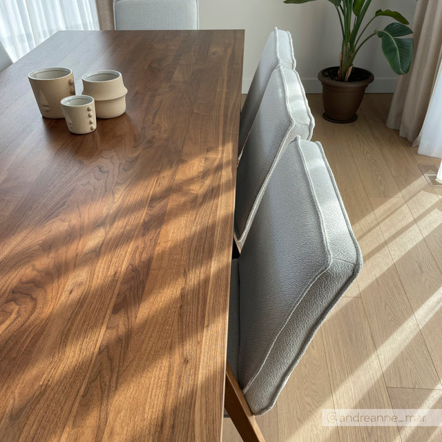 Table en bois avec chaises grises modernes et tasses en ceramique, baignee de lumiere naturelle.