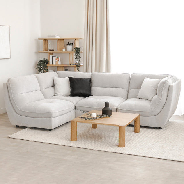 Canape sectionnel gris clair moderne avec coussins noirs et blancs, table basse bois clair.