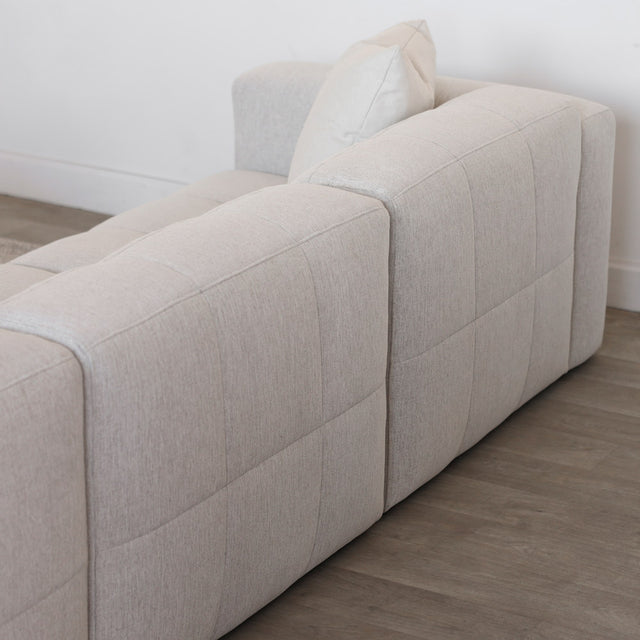 Vue arriere d un canape d angle beige clair au design moderne et matelasse.