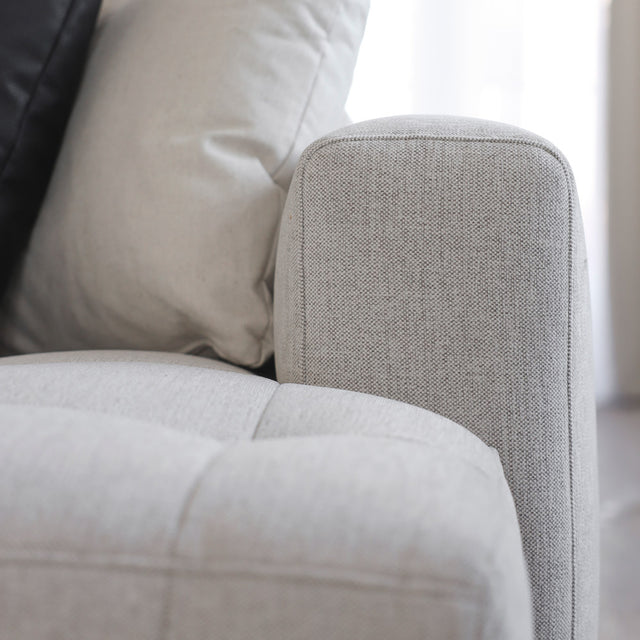 Accoudoir et coussins d un canape beige clair en tissu texture au style moderne.