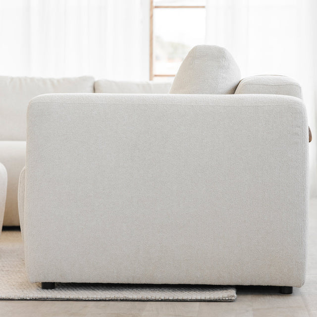 vue laterale d un canape beige clair en tissu boucle sur tapis creme.