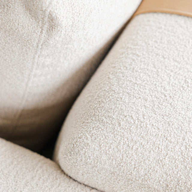 gros plan sur tissu boucle beige clair du canape avec detail de sangle en cuir.