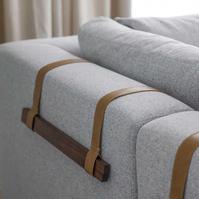 dos de canape gris clair avec sangles en cuir beige et barres en bois fonce.
