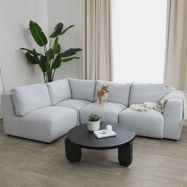 canape d angle gris clair dans salon moderne avec table basse noire et plante verte.