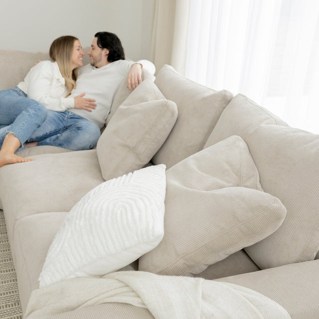 Canape beige en velours cotele avec coussins creme dans un salon lumineux et cosy.