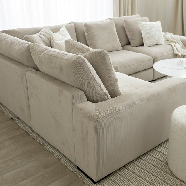 Canape d angle beige en velours cotele avec coussins creme et table basse blanche moderne.