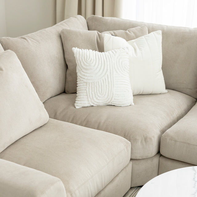 Canape d angle beige en velours cotele avec coussins decoratifs blancs.