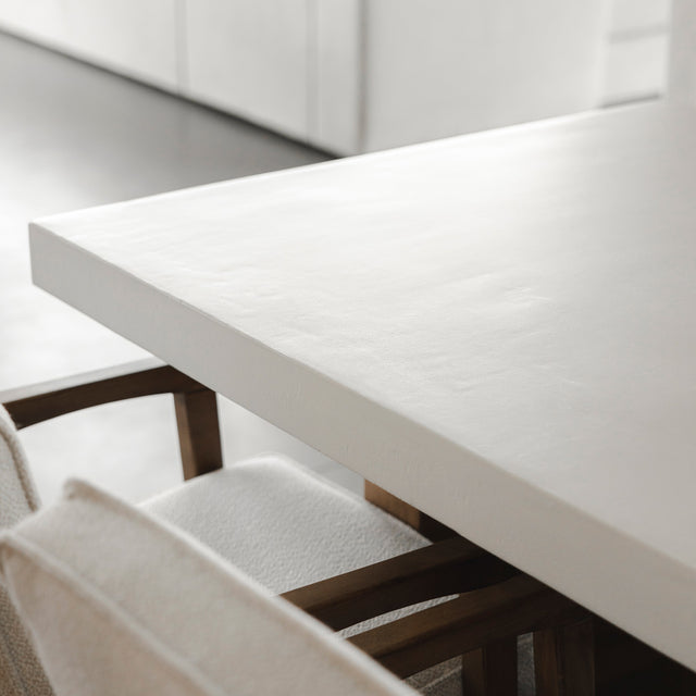 bord de table en beton blanc avec chaises beige et accoudoirs en bois.