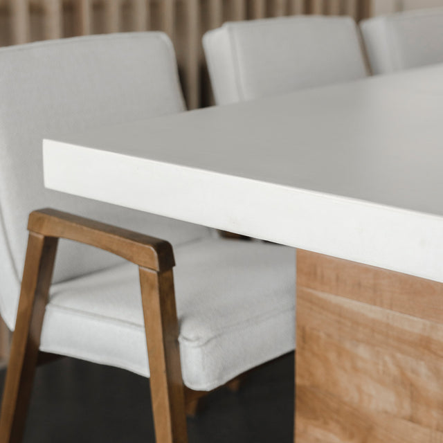 bord de table en beton clair avec pied en bois et chaises beige modernes.