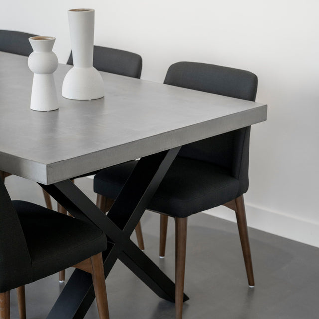 table en beton gris avec pieds croises noirs et chaises noires modernes.