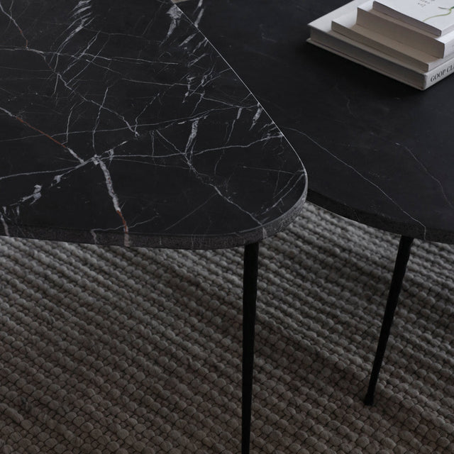 Detail de deux plateaux en marbre noir veine blanche sur pieds metalliques fins.