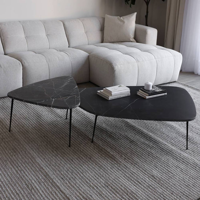 Duo de tables basses en marbre noir avec pieds fins metalliques devant canape beige clair.