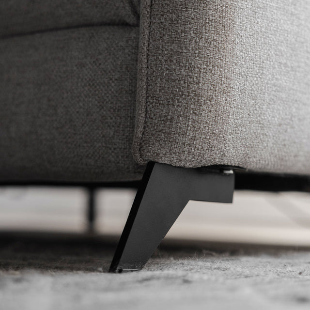 gros plan sur le pied metallique noir du canape en tissu gris, detail de finition elegante.