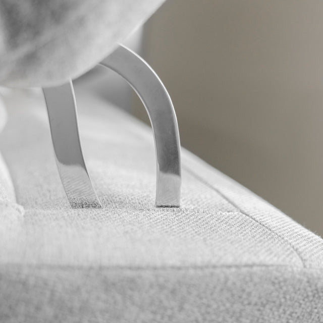 detail du mecanisme metalique de tetiere reglable sur canape clair en tissu.