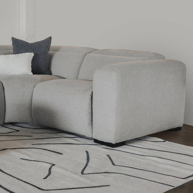 canape d angle gris clair avec coussins decoratifs sur tapis a motifs abstraits.