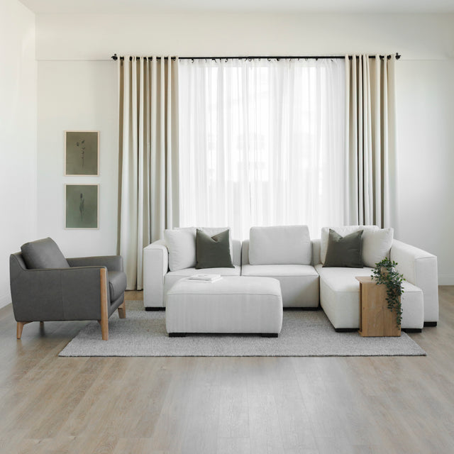 Salon moderne avec canape d angle beige, fauteuil en cuir gris et deco minimaliste.
