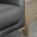 zoom sur la base en bois clair et le revetement en cuir gris du fauteuil.
