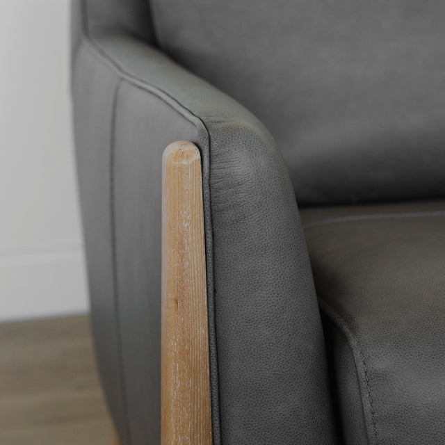 detail de l accoudoir en cuir gris et finition en bois clair du fauteuil.
