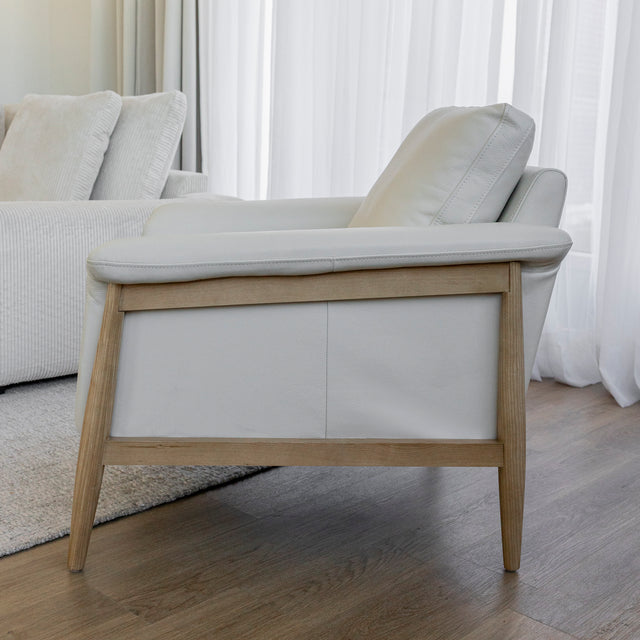 Fauteuil en cuir crème avec structure en bois clair dans un salon lumineux.