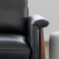 Image rapprochée d'un fauteuil en cuir noir avec structure en bois dans un salon moderne.