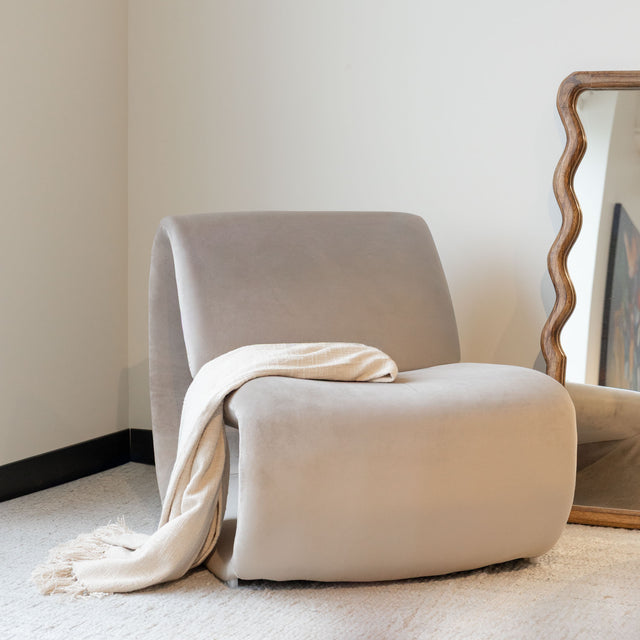 Fauteuil lounge beige avec jeté, dans un salon minimaliste.