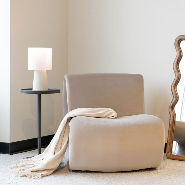 Fauteuil lounge beige avec jeté, dans un salon minimaliste.