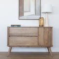 Buffet en bois clair style scandinave avec portes rainurées, pieds inclinés et déco minimaliste dans un salon moderne.