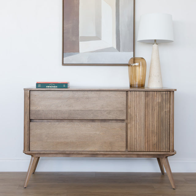 Buffet en bois clair style scandinave avec portes rainurées, pieds inclinés et déco minimaliste dans un salon moderne.