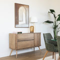 Buffet en bois clair style scandinave avec portes rainurées, pieds inclinés et déco minimaliste dans un salon moderne.