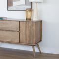 Buffet en bois clair style scandinave avec portes rainurées, pieds inclinés et déco minimaliste dans un salon moderne.