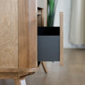 Buffet bas en bois clair avec tiroirs et porte rainurée, design scandinave sur pieds compas dans un intérieur épuré.