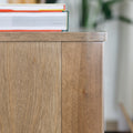 Buffet bas en bois clair avec tiroirs et porte rainurée, design scandinave sur pieds compas dans un intérieur épuré.