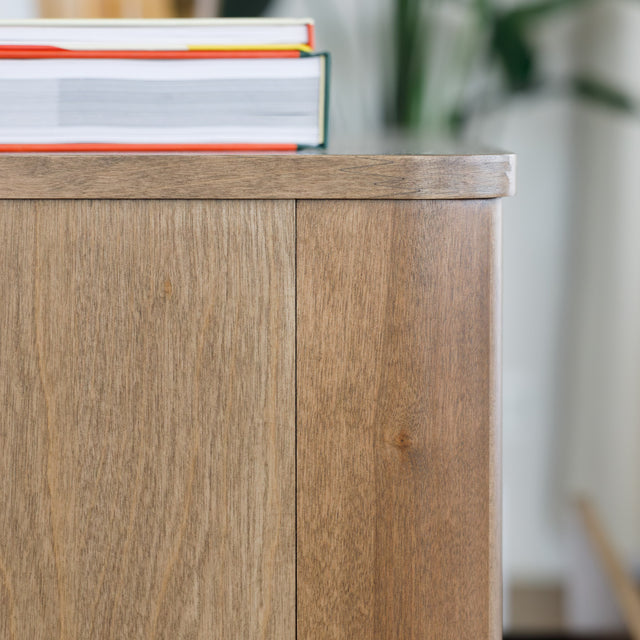Buffet bas en bois clair avec tiroirs et porte rainurée, design scandinave sur pieds compas dans un intérieur épuré.