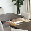 Table à manger rectangulaire en bois foncé avec six chaises rembourrées dans une salle à manger lumineuse.