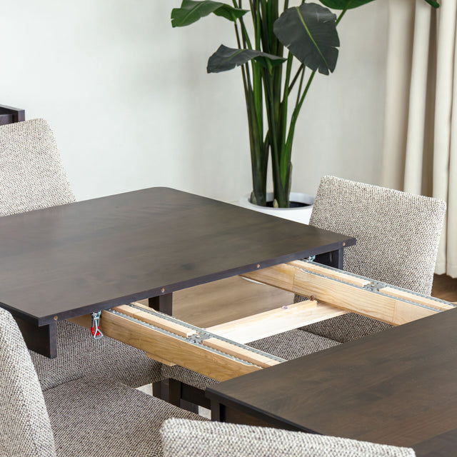 Table à manger rectangulaire en bois foncé avec six chaises rembourrées dans une salle à manger lumineuse.