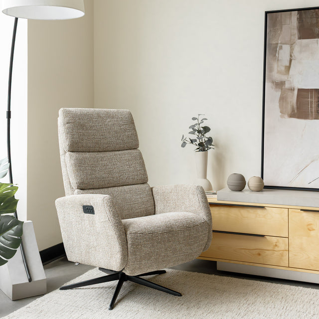Fauteuil en tissu beige avec dossier inclinable et base pivotante, dans un salon lumineux et épuré.