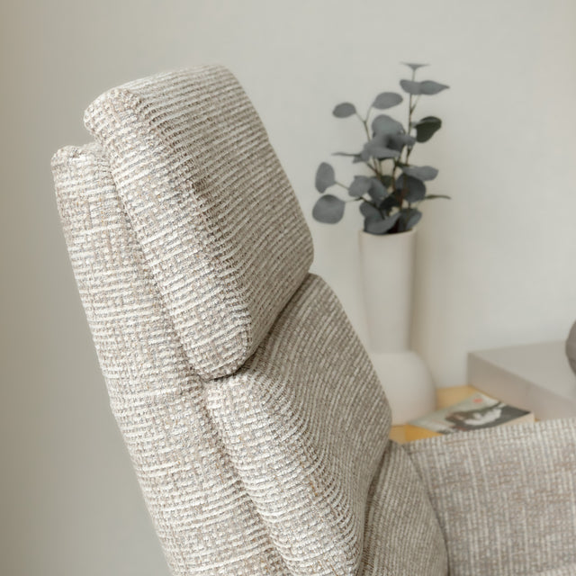 Fauteuil en tissu beige avec dossier inclinable et base pivotante, dans un salon lumineux et épuré.