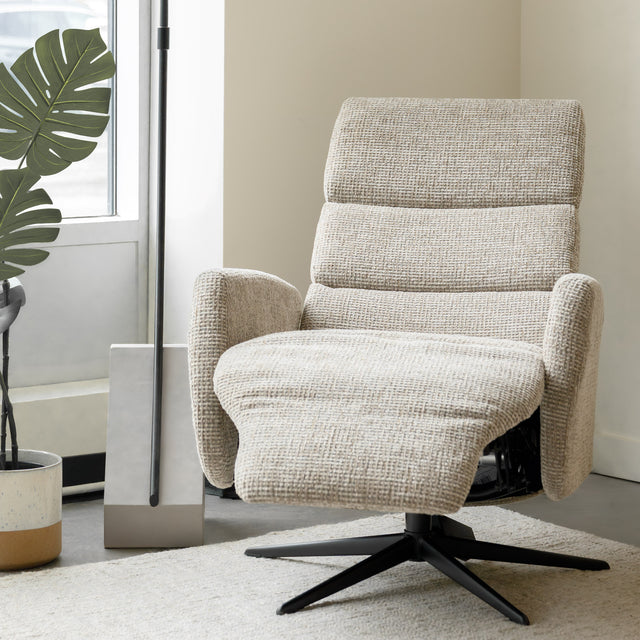 Fauteuil en tissu beige avec dossier inclinable et base pivotante, dans un salon lumineux et épuré.