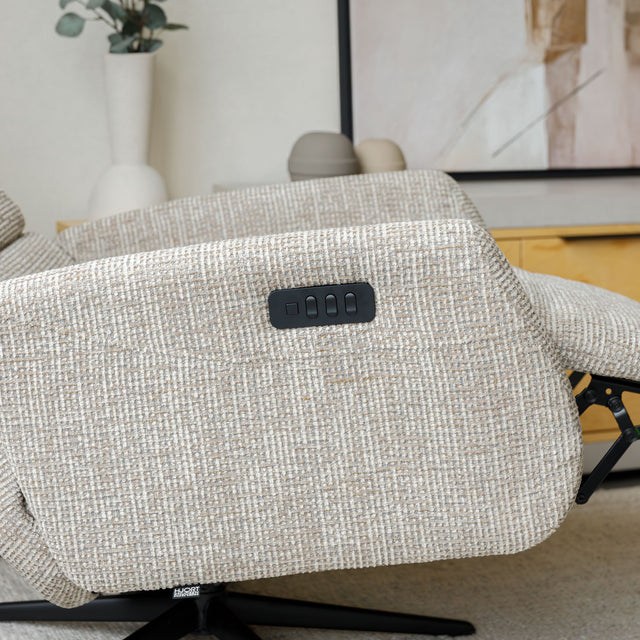 Fauteuil en tissu beige avec dossier inclinable et base pivotante, dans un salon lumineux et épuré.