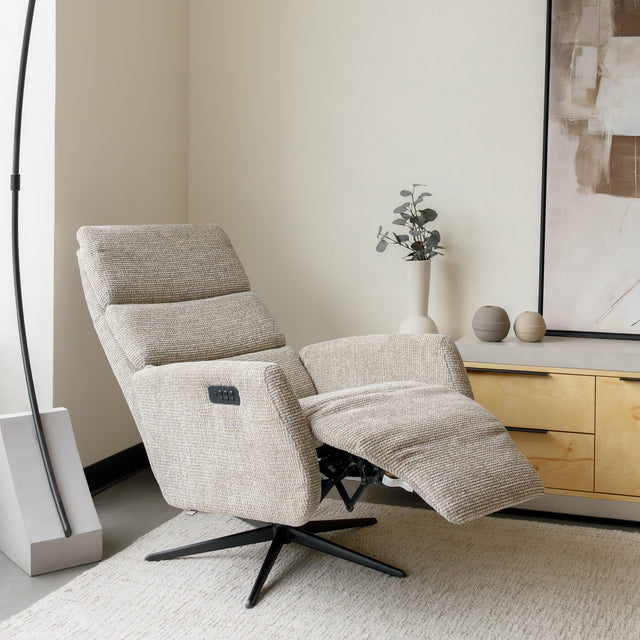 Fauteuil en tissu beige avec dossier inclinable et base pivotante, dans un salon lumineux et épuré.