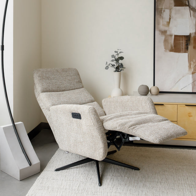 Fauteuil en tissu beige avec dossier inclinable et base pivotante, dans un salon lumineux et épuré.