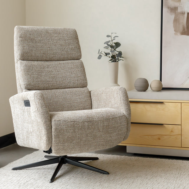 Fauteuil en tissu beige avec dossier inclinable et base pivotante, dans un salon lumineux et épuré.