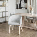 Chaise moderne en tissu crème avec pieds en bois clair dans une salle a manger minimaliste.