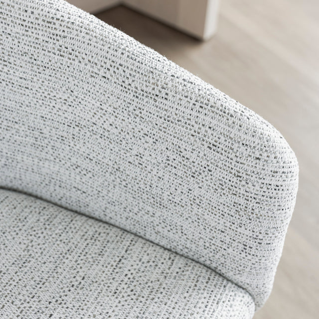 Image rapprochée d'une chaise moderne en tissu crème avec pieds en bois clair dans une salle a manger minimaliste.